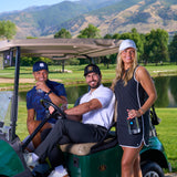 Two men in a golf cart with a woman standing next to them, all of whom are wearing Black Clover Live Lucky apparel. 