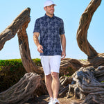 Man standing next to petrified wood wearing Black Clover Live Lucky hat in white.